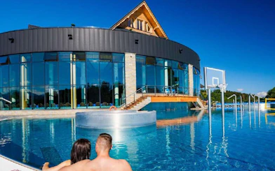 Couple relaxing in outdoor pool at Chocholow Thermal Baths Saunarium, Poland.