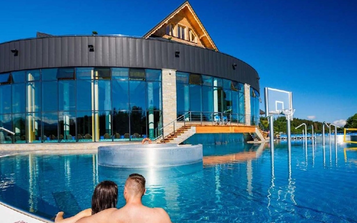 Couple relaxing in outdoor pool at Chocholow Thermal Baths Saunarium, Poland.