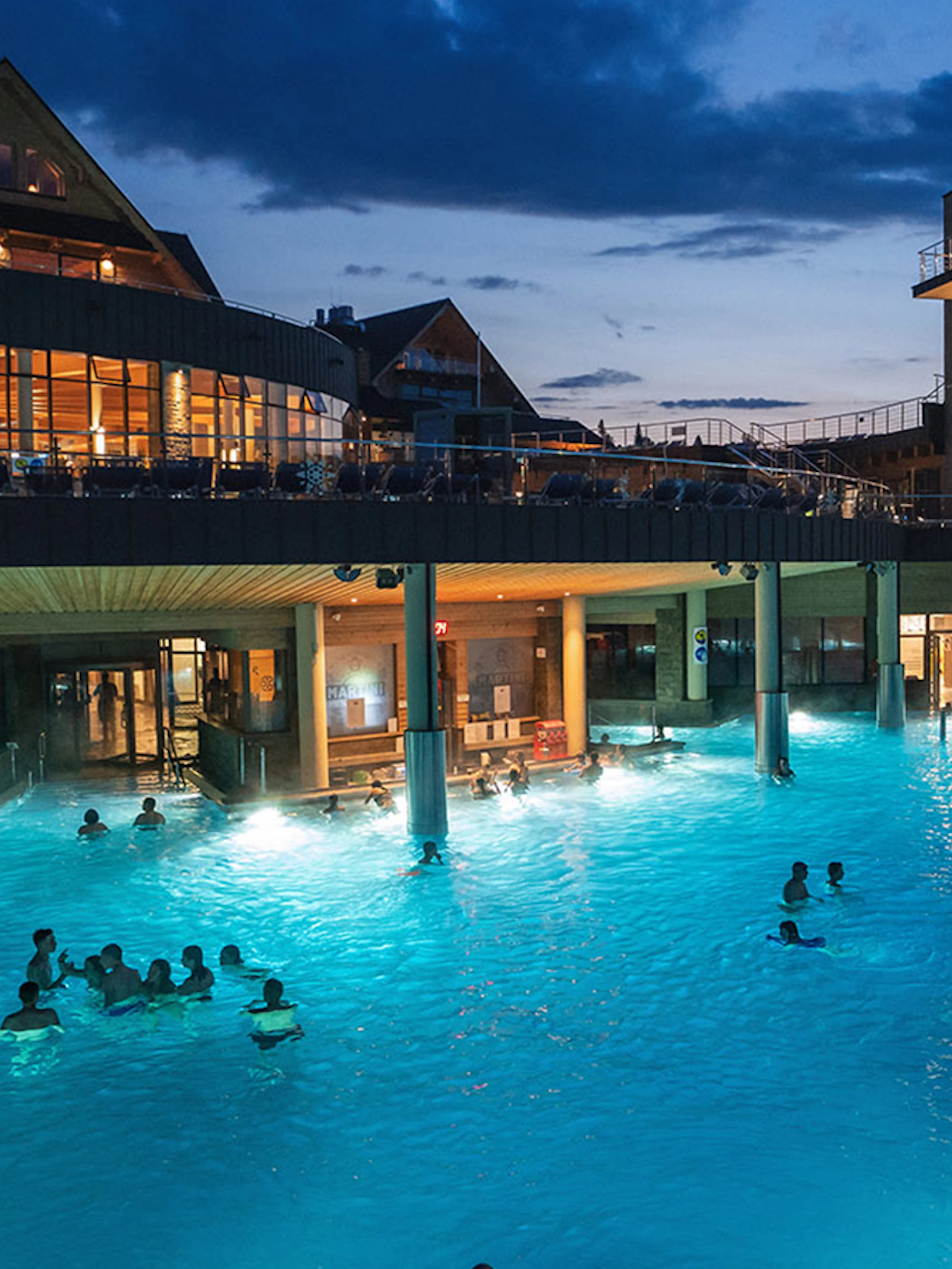 Chocholow Thermal Baths' Saunarium at night with visitors enjoying the illuminated pools.