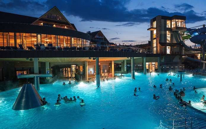 Chocholow Thermal Baths' Saunarium at night with visitors enjoying the illuminated pools.