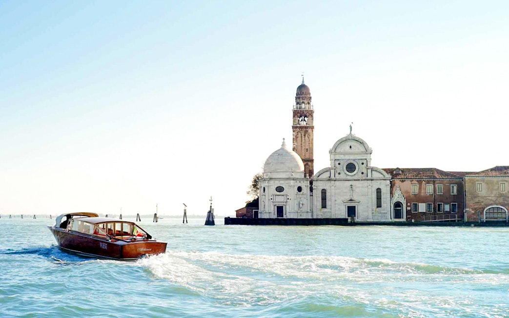 Private water taxi on Venetian lagoon near historic buildings, Venice transfer service.