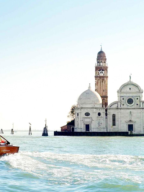Private water taxi on Venetian lagoon near historic buildings, Venice transfer service.