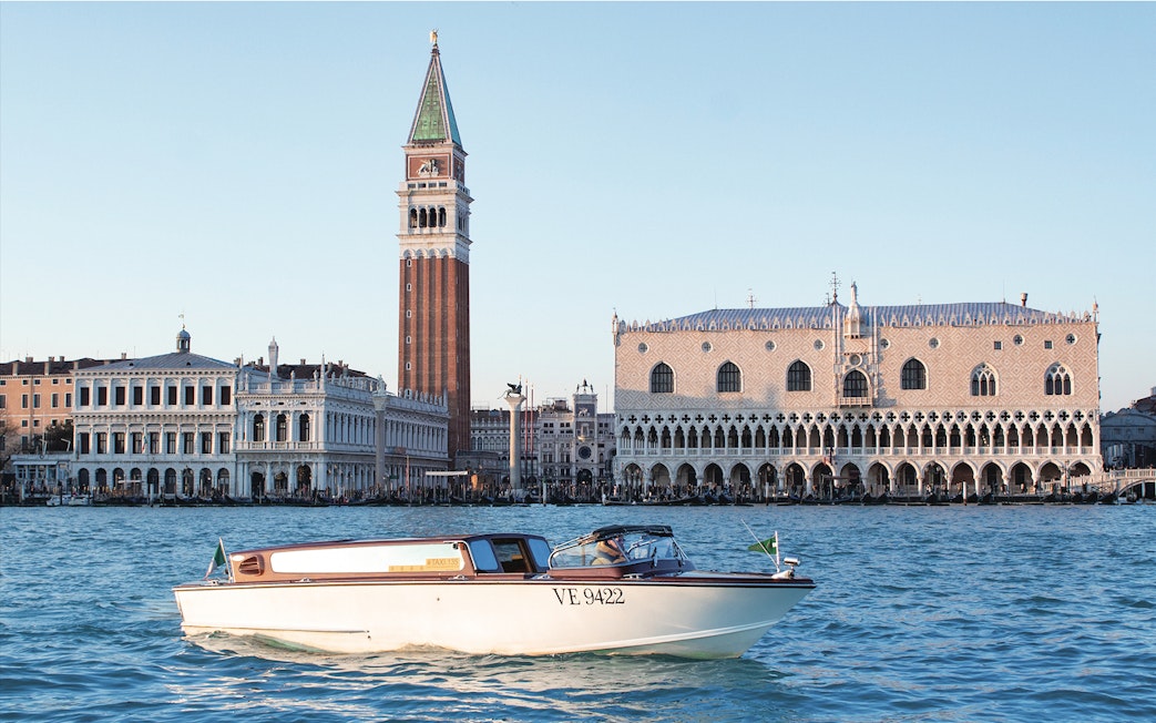 Water taxi cruising near Doge's Palace and St. Mark's Campanile in Venice.