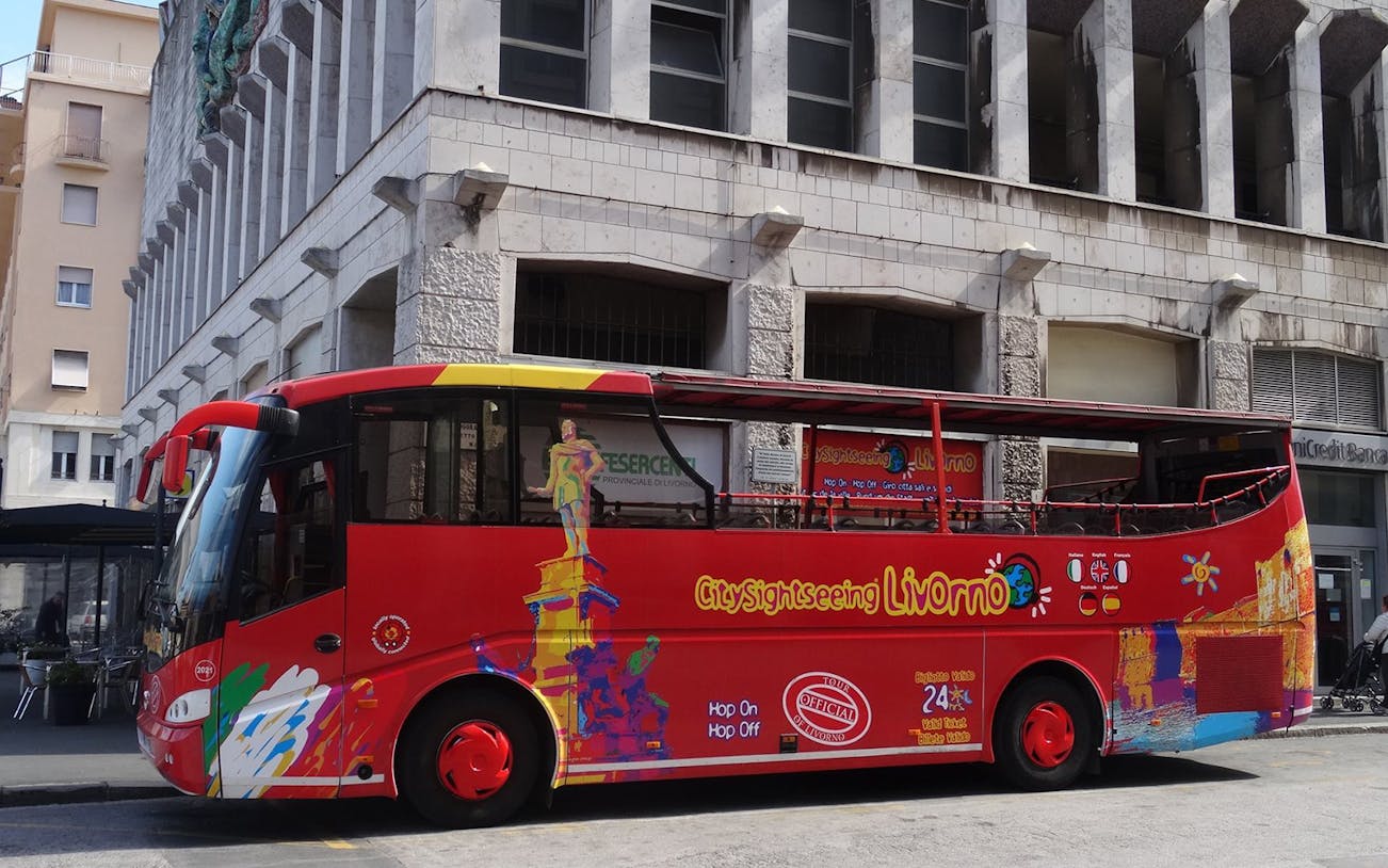 Red Livorno sightseeing bus parked in front of a building, part of 24-hour hop-on-hop-off tour.