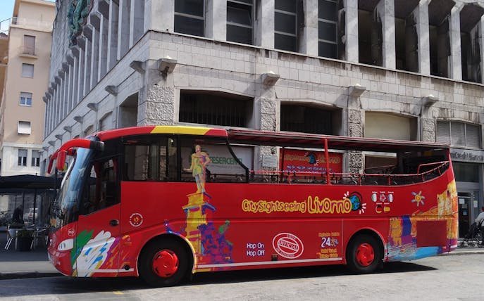 Red Livorno sightseeing bus parked in front of a building, part of 24-hour hop-on-hop-off tour.