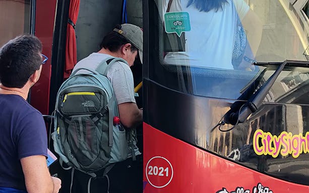Tourists boarding a red City Sightseeing bus in Livorno for a hop-on-hop-off tour.