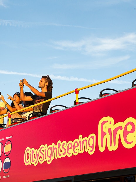 Tourists on an open-top bus during a Florence sightseeing tour.
