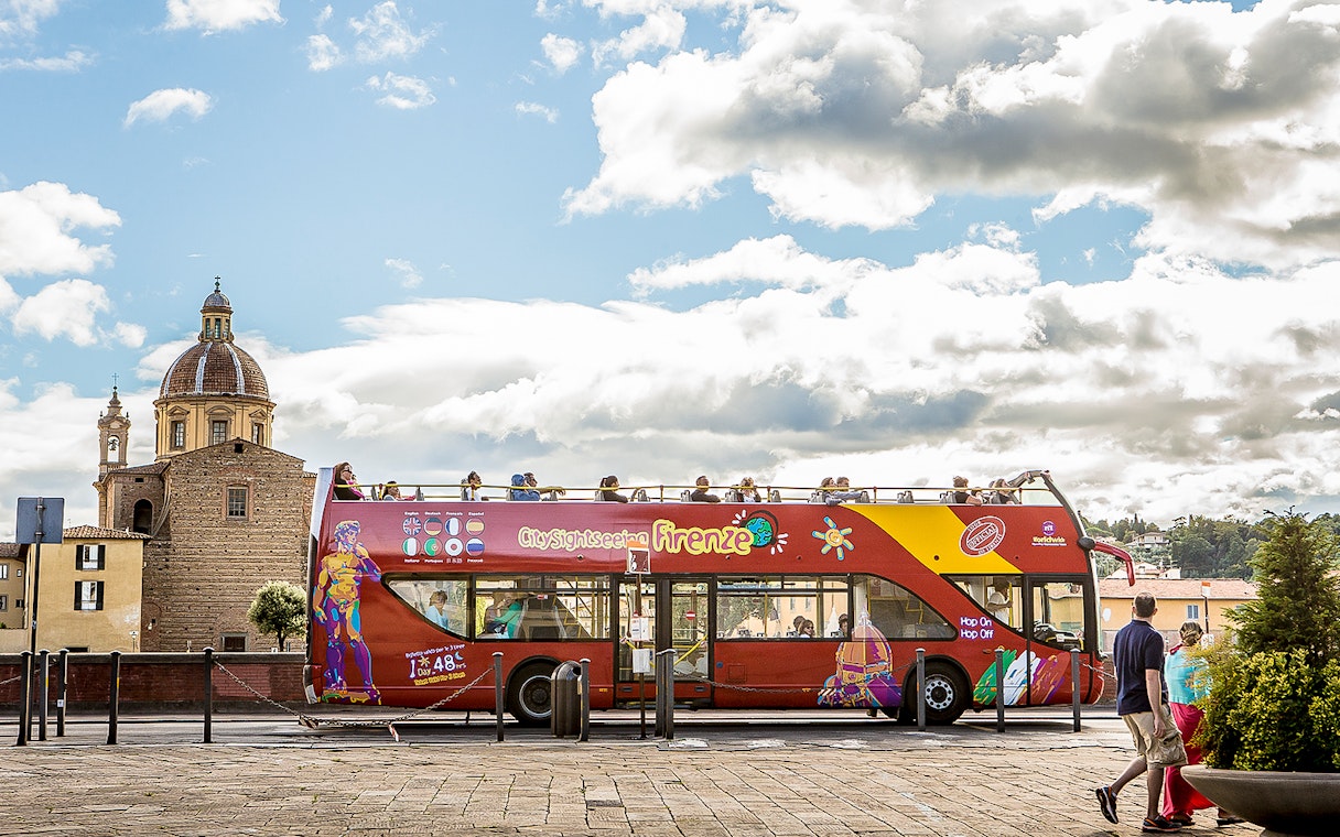 Open-top sightseeing bus in Florence near a historic church.