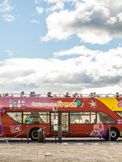 Open-top sightseeing bus in Florence near a historic church.
