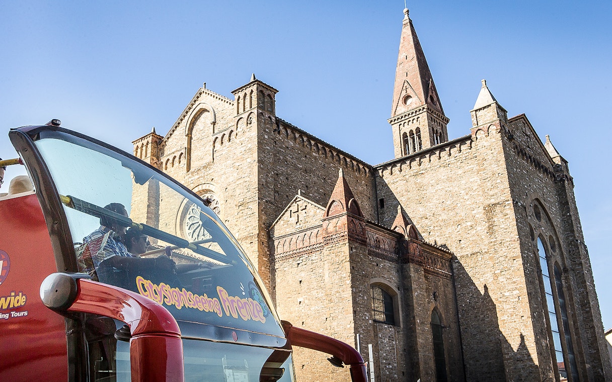 Hop-on hop-off bus near historic building in Florence, Italy.