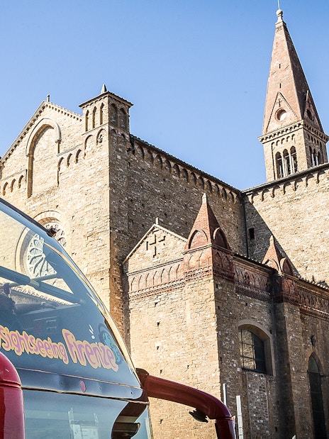 Hop-on hop-off bus near historic building in Florence, Italy.