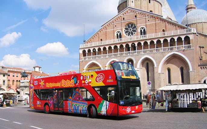 Red double-decker bus in front of Basilica of Saint Anthony, Padua, Italy.