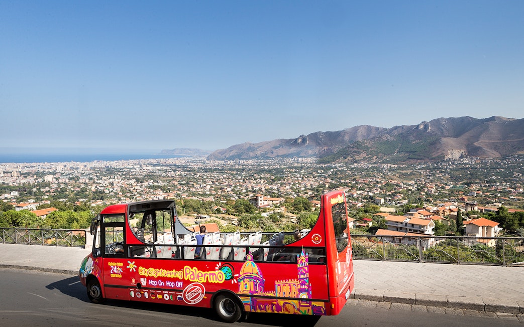 Palermo hop-on hop-off bus with city and mountain view in the background.
