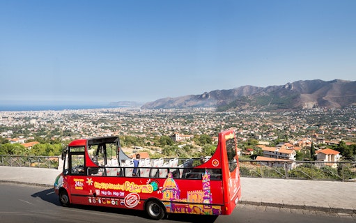 Palermo hop-on hop-off bus with city and mountain view in the background.