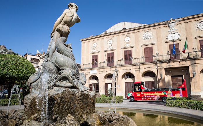 Palermo fountain with City Sightseeing hop-on hop-off bus in front of historic building.