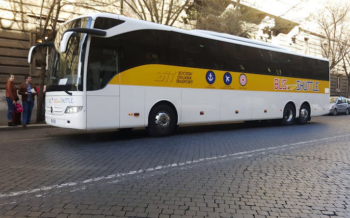 Shuttle bus parked on cobblestone street for transfers between Civitavecchia Port and Rome.