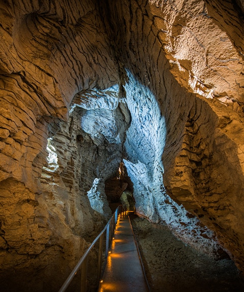 Guided walkway through Ruakuri Cave with illuminated limestone formations.