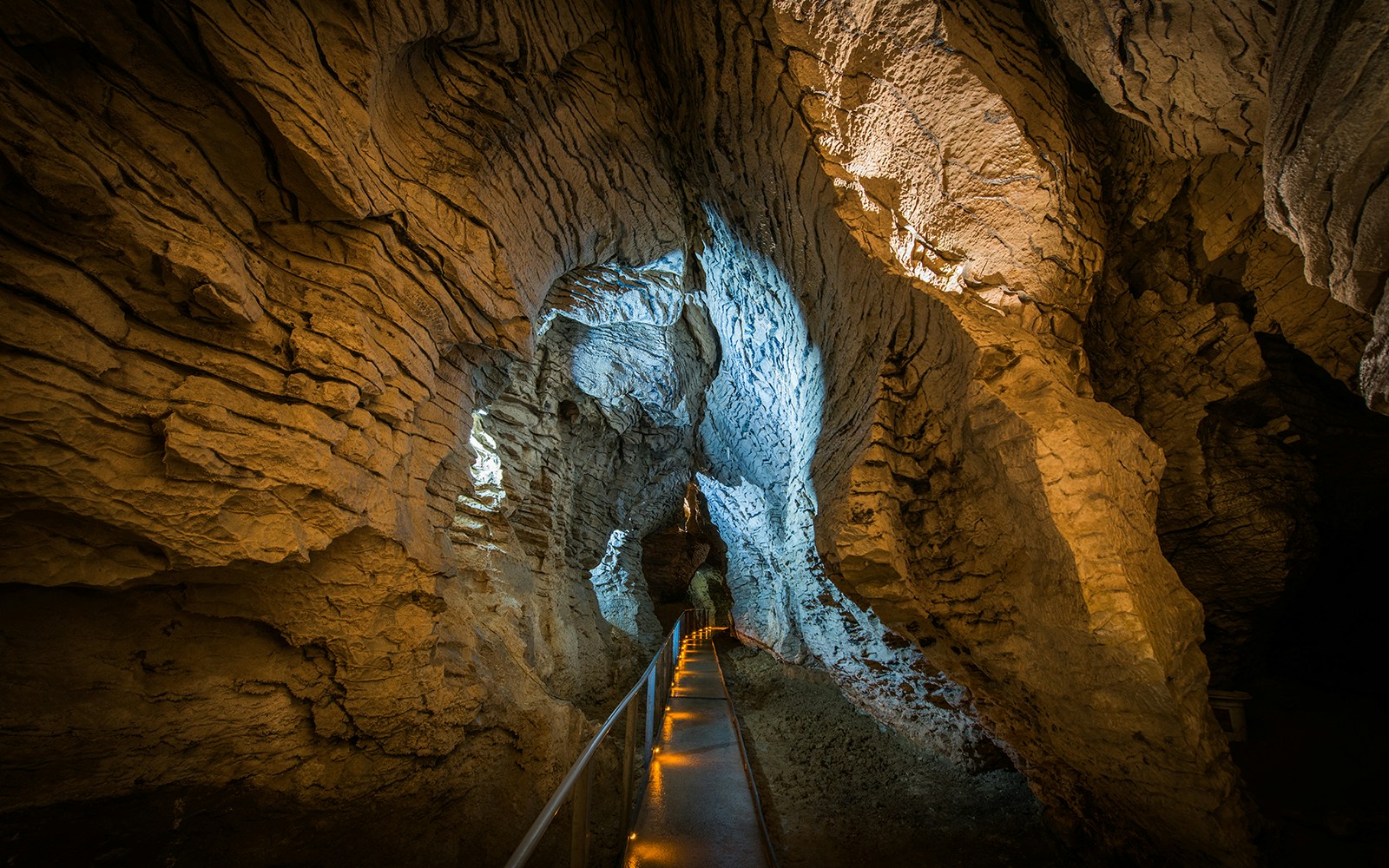 Guided walkway through Ruakuri Cave with illuminated limestone formations.