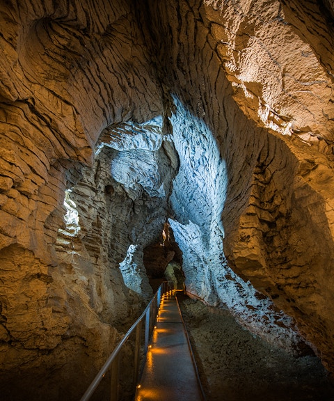 Guided walkway through Ruakuri Cave with illuminated limestone formations.