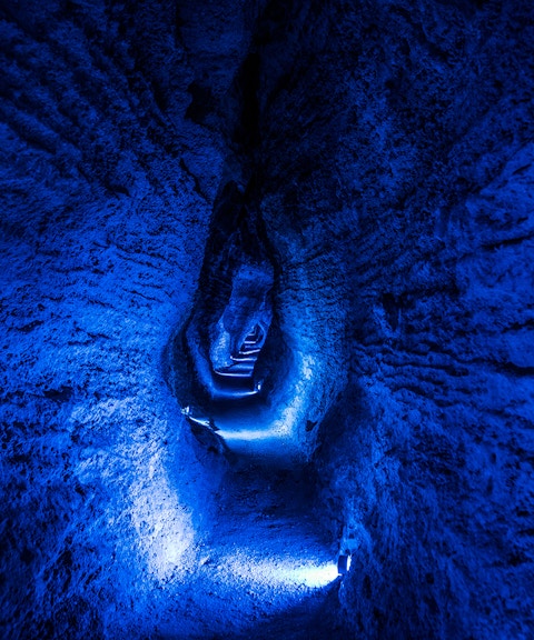 Ruakuri Cave illuminated passageway with textured rock walls, New Zealand.