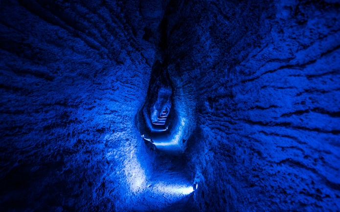Ruakuri Cave illuminated passageway with textured rock walls, New Zealand.