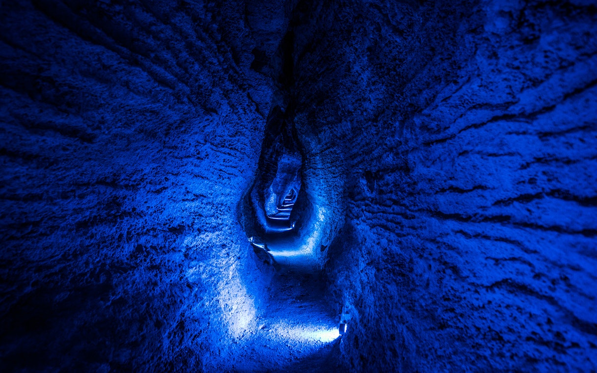 Ruakuri Cave illuminated passageway with textured rock walls, New Zealand.