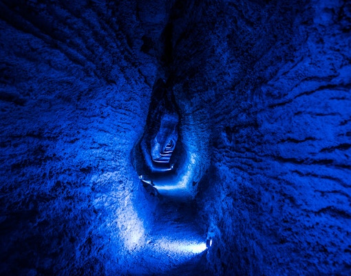 Ruakuri Cave illuminated passageway with textured rock walls, New Zealand.