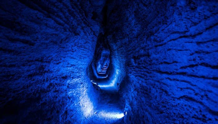 Ruakuri Cave illuminated passageway with textured rock walls, New Zealand.