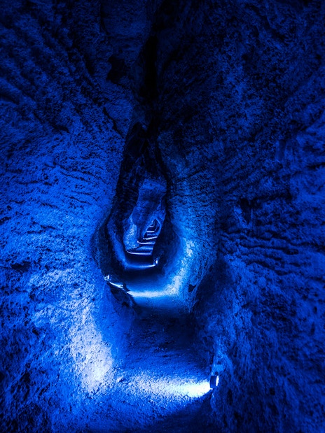 Ruakuri Cave illuminated passageway with textured rock walls, New Zealand.