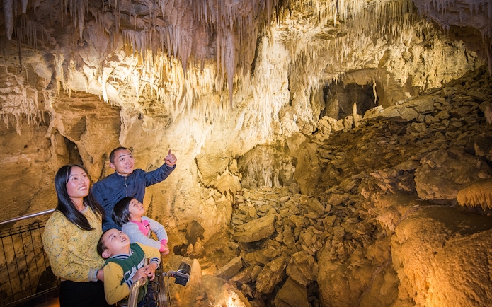 Family exploring stalactites in Aranui Cave, Waitomo during guided tour.
