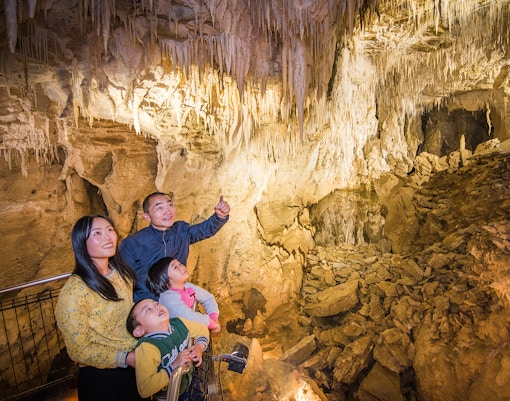 Family exploring stalactites in Aranui Cave, Waitomo during guided tour.