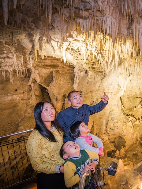 Family exploring stalactites in Aranui Cave, Waitomo during guided tour.