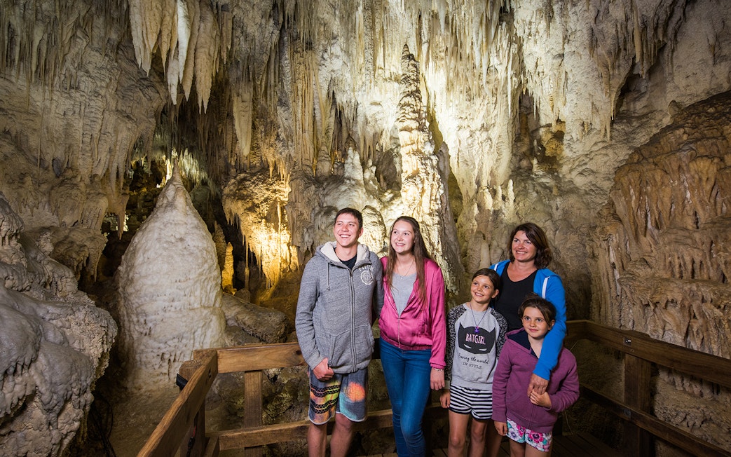 Guided tour group exploring limestone formations inside Aranui Cave, Waitomo, New Zealand.