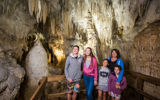Guided tour group exploring limestone formations inside Aranui Cave, Waitomo, New Zealand.