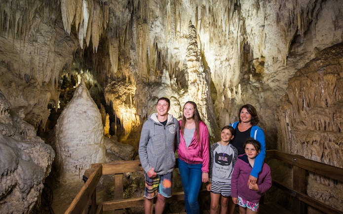 Guided tour group exploring limestone formations inside Aranui Cave, Waitomo, New Zealand.