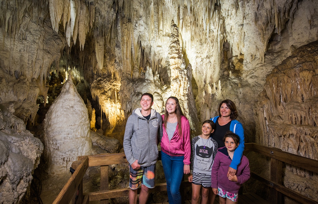 Guided tour group exploring limestone formations inside Aranui Cave, Waitomo, New Zealand.