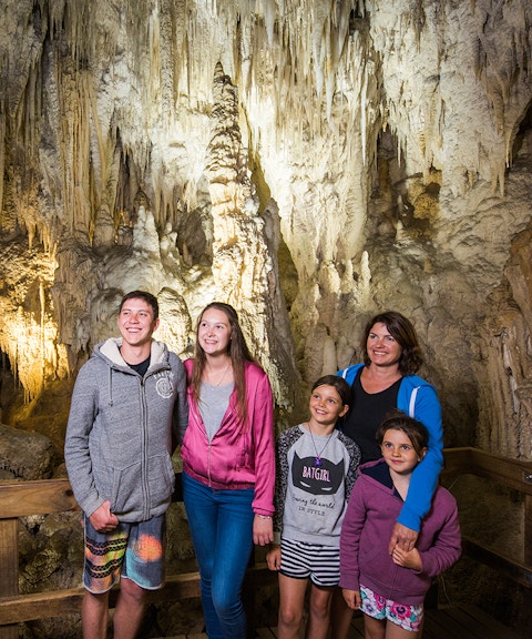 Guided tour group exploring limestone formations inside Aranui Cave, Waitomo, New Zealand.