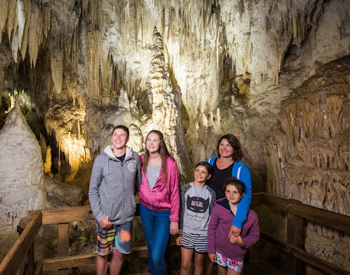 Guided tour group exploring limestone formations inside Aranui Cave, Waitomo, New Zealand.