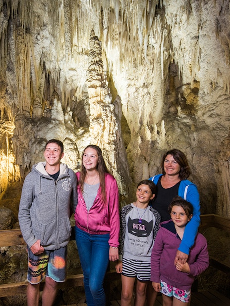 Guided tour group exploring limestone formations inside Aranui Cave, Waitomo, New Zealand.