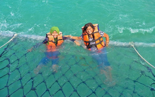 Tourists swimming in safety nets on the Dickson Dragon Cruise, Port Dickson, Malaysia.