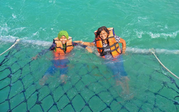 Tourists swimming in safety nets on the Dickson Dragon Cruise, Port Dickson, Malaysia.