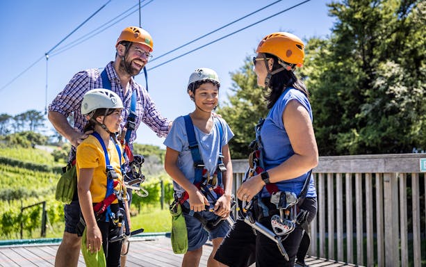 Family preparing for zipline adventure in Waiheke forest.