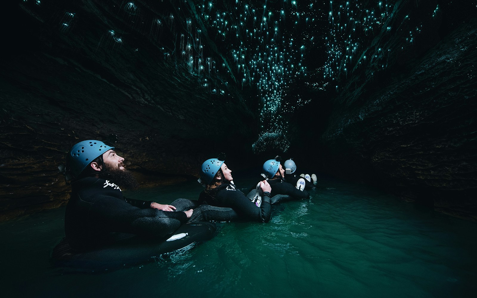 Adventurers black water rafting under glowworms in Waitomo cave.