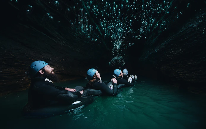 Adventurers black water rafting under glowworms in Waitomo cave.