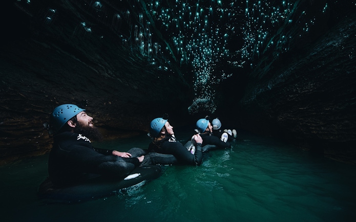 Adventurers black water rafting under glowworms in Waitomo cave.