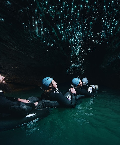 Adventurers black water rafting under glowworms in Waitomo cave.