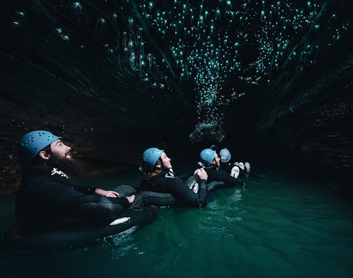 Adventurers black water rafting under glowworms in Waitomo cave.