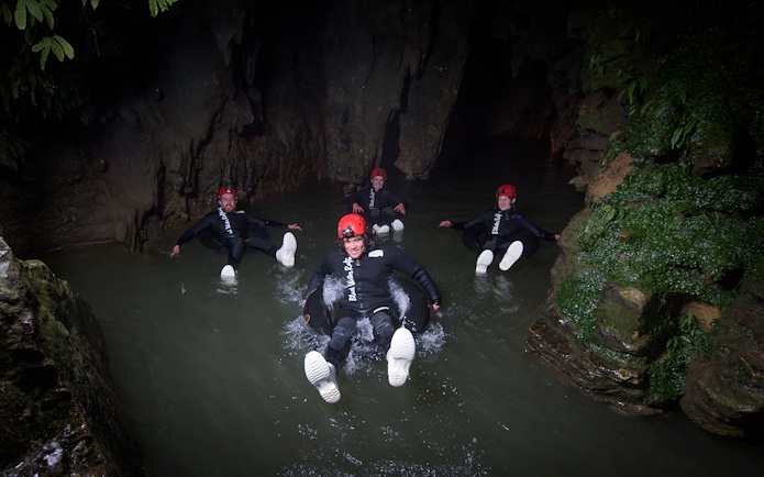 Adventurers black water rafting in a cave during a guided experience in Waitomo.