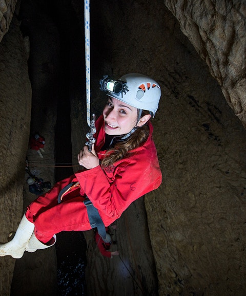 Caver descending in Waitomo cave during Black Abyss tour with zip lining and rafting.