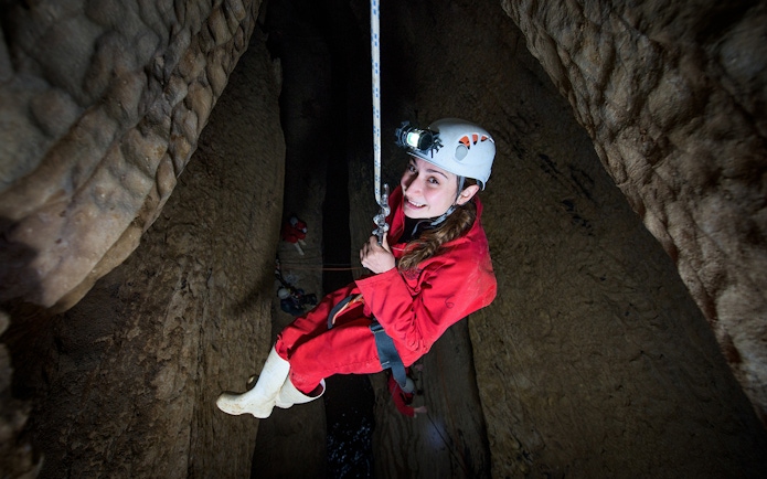 Caver descending in Waitomo cave during Black Abyss tour with zip lining and rafting.